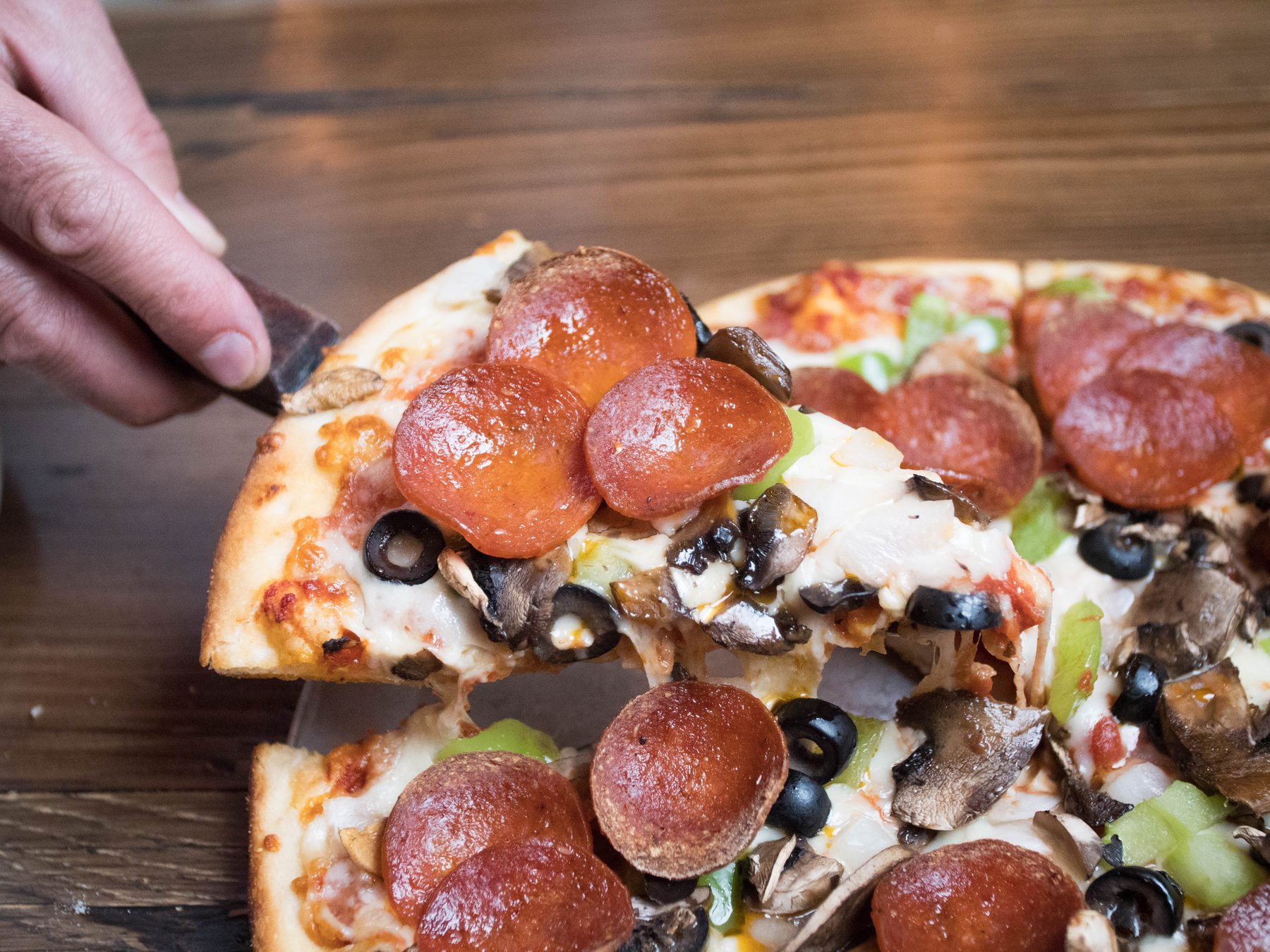 A gooey slice of Litzas pepperoni pizza being lifted